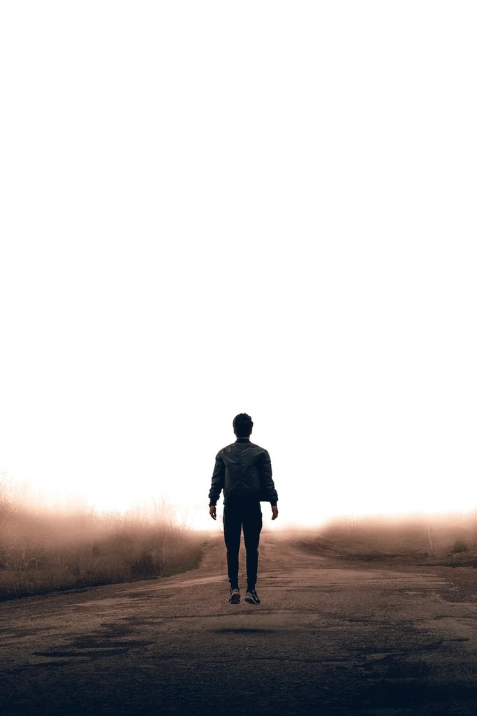 Silueta de un hombre caminando hacia la luz entre la niebla